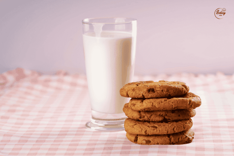 Glass of milk with stacked cookies on a pink checkered cloth showing the role of milk in cookie texture.